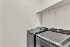 Dedicated laundry area featuring a wall-mounted shelf, light-toned walls, and space for appliances