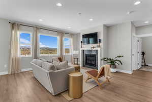 Bright living area featuring wood-finish flooring, recessed lighting, and a contemporary fireplace with dark tile surround and a white mantel
