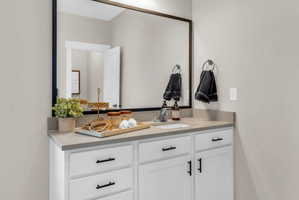 Bathroom vanity with white cabinetry, a light-toned countertop, and a rectangular undermount sink
