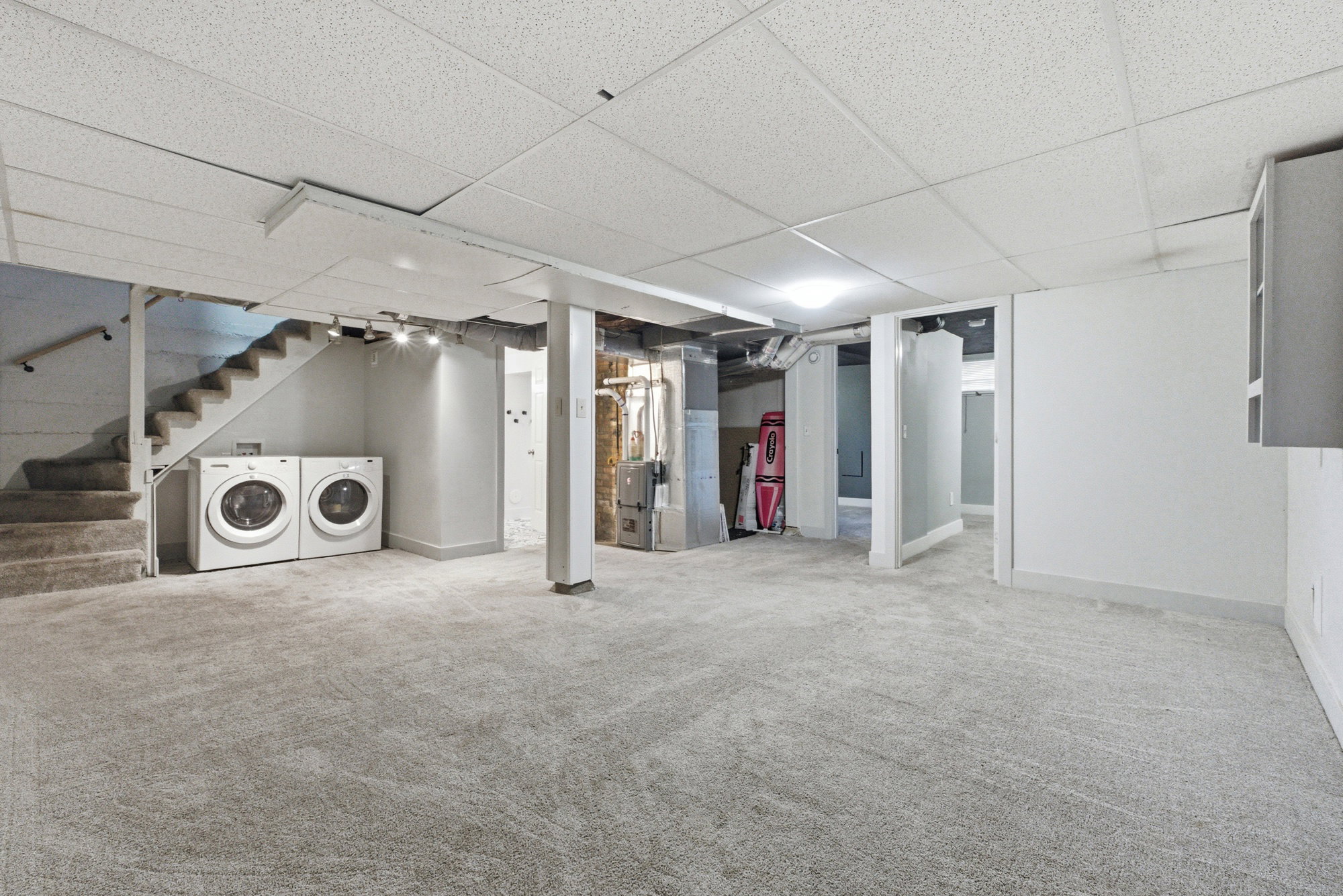 Spacious basement family room with carpet, laundry hookups, stair access, and room for multiple uses.