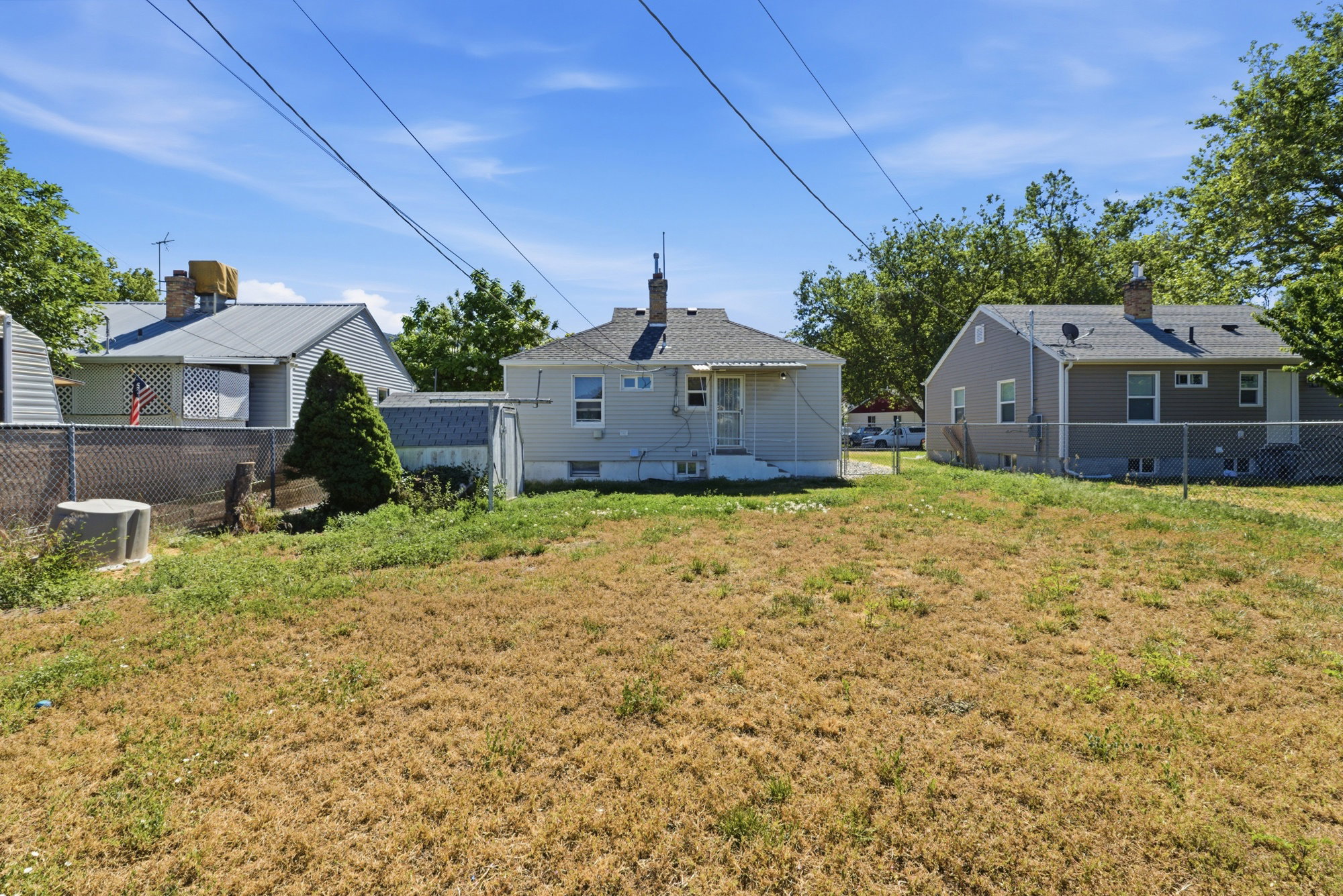 Rear yard view with generous outdoor space, fenced perimeter, and back entrance to the home.