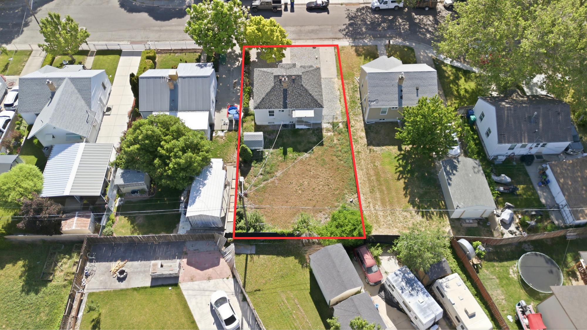 Aerial lot view highlighting the property boundaries, home placement, backyard, and front parking area.