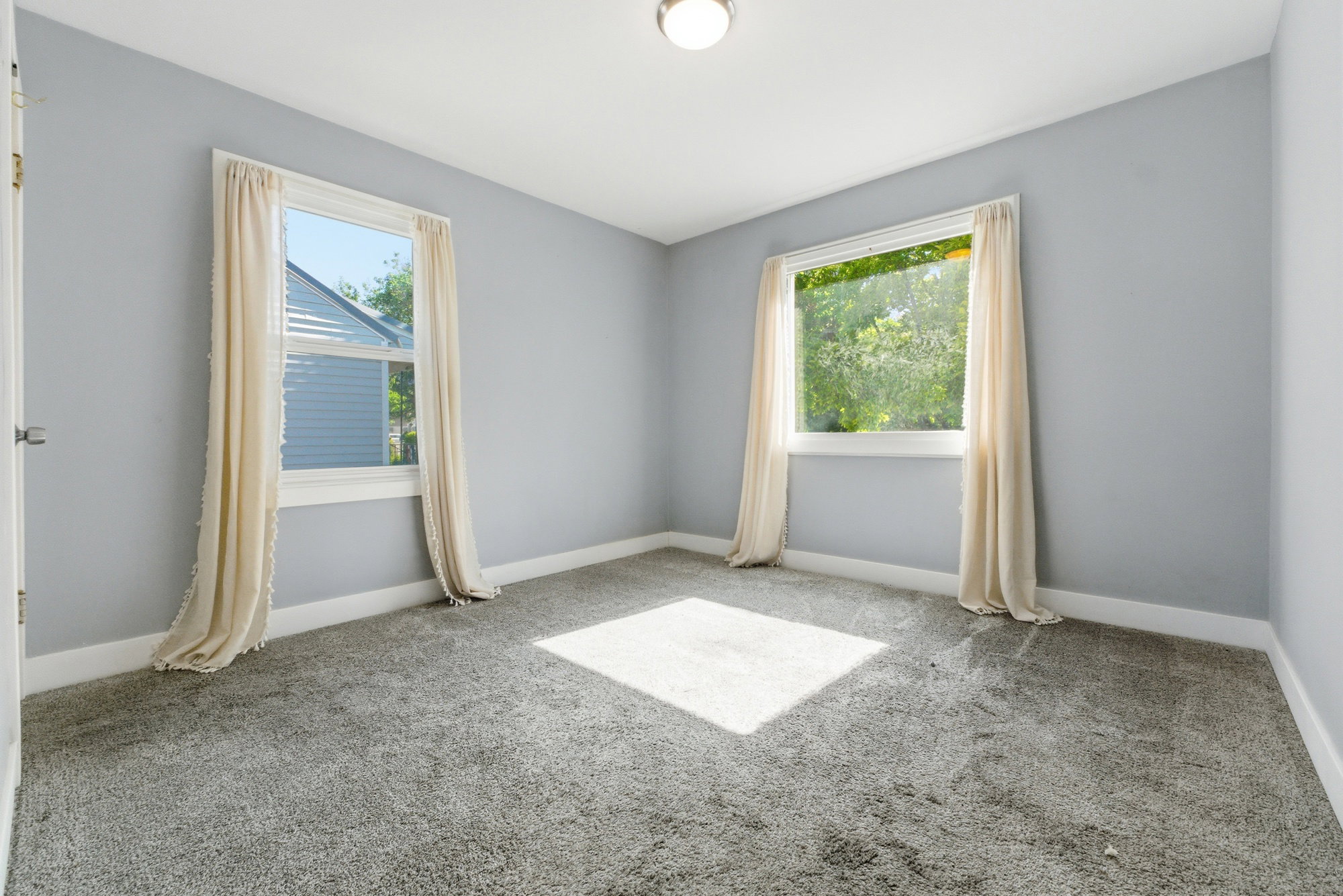 Bedroom with soft carpet, gray walls, white trim, two windows, and great natural light.