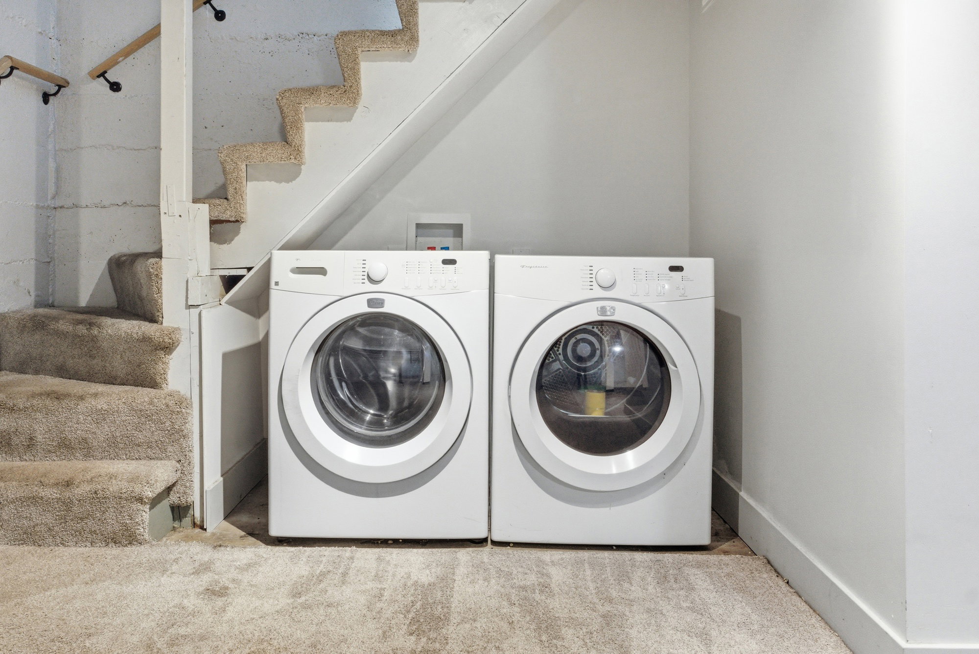 Laundry area conveniently located near the stairs with front-load washer and dryer included.