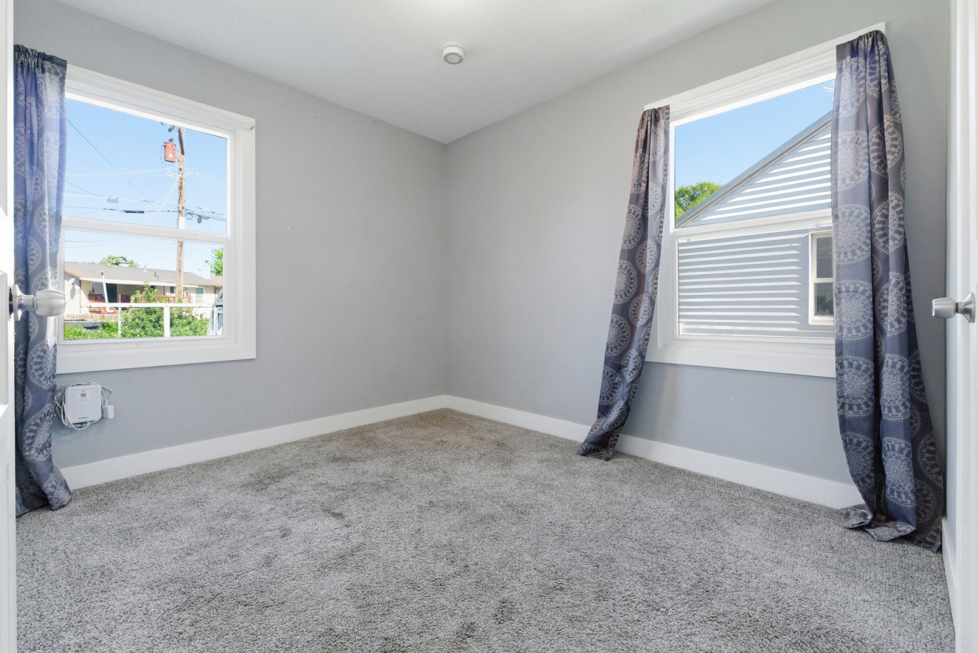 Bedroom featuring soft carpet, gray walls, white trim, two windows, and great natural light.