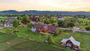 Expansive property featuring a brown ranch-style residence with a covered patio, a detached barn-style structure with a metal roof, and a large manicured lawn