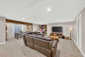 Spacious entertainment room featuring recessed ceiling lighting, light-toned carpet flooring, and a window with horizontal blinds