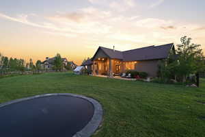 Expansive green lawn with mature trees and a built-in trampoline