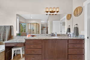 Spacious vanity featuring a light granite countertop, dark wood-finish cabinetry, a built-in makeup area, and an integrated sink with a dark-finish faucet
