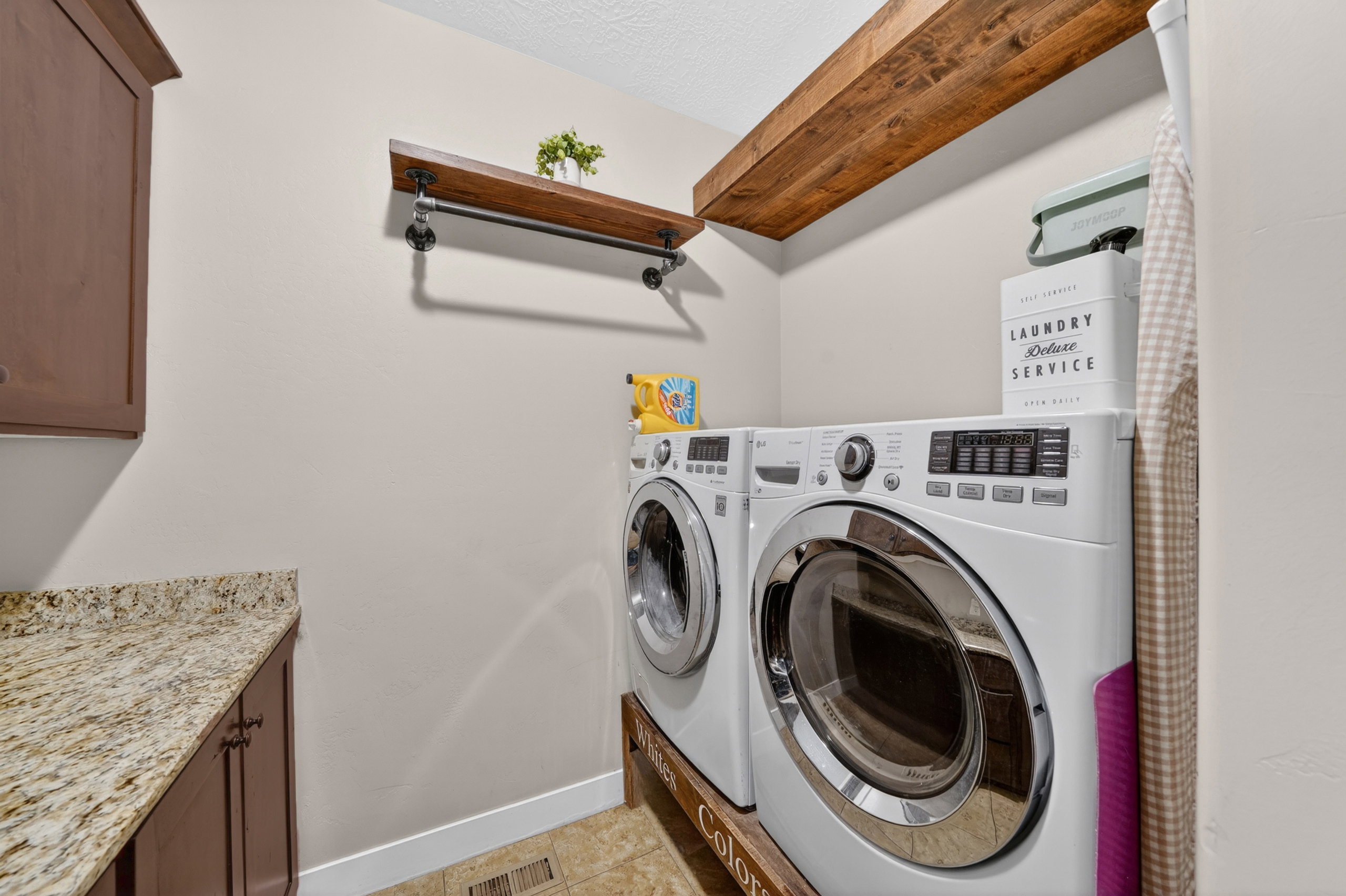 Laundry area featuring built-in cabinetry, stone-finish countertops, wood-finish shelving, and wood-finish flooring