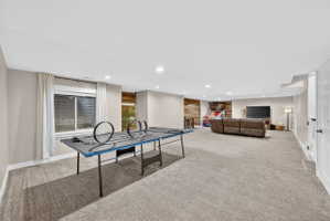 Spacious carpeted room featuring recessed lighting, a window with blinds, and an accent wall with horizontal wood paneling