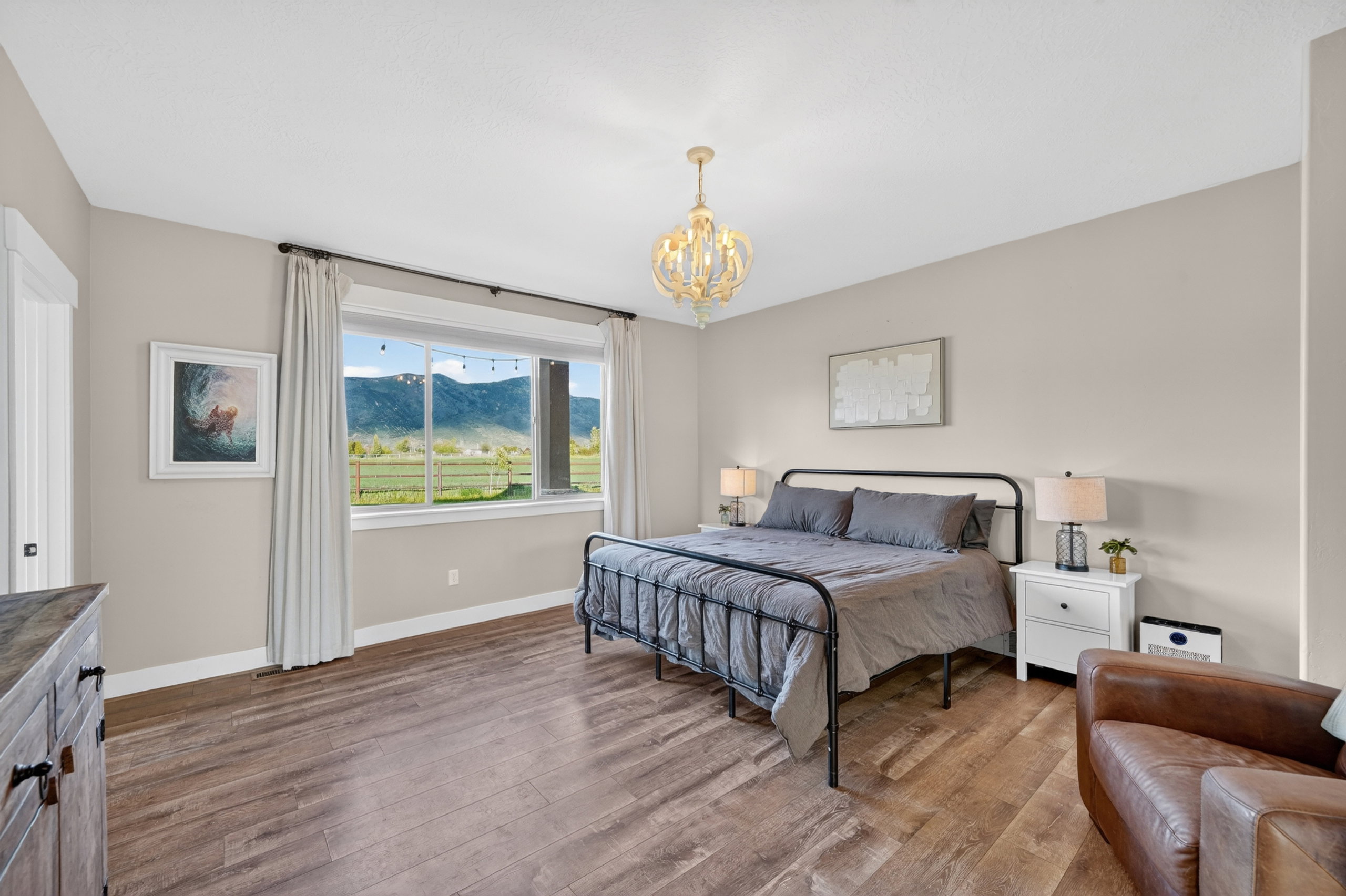 Bedroom featuring wood-finish flooring, a contemporary chandelier, neutral wall tones, and a large picture window