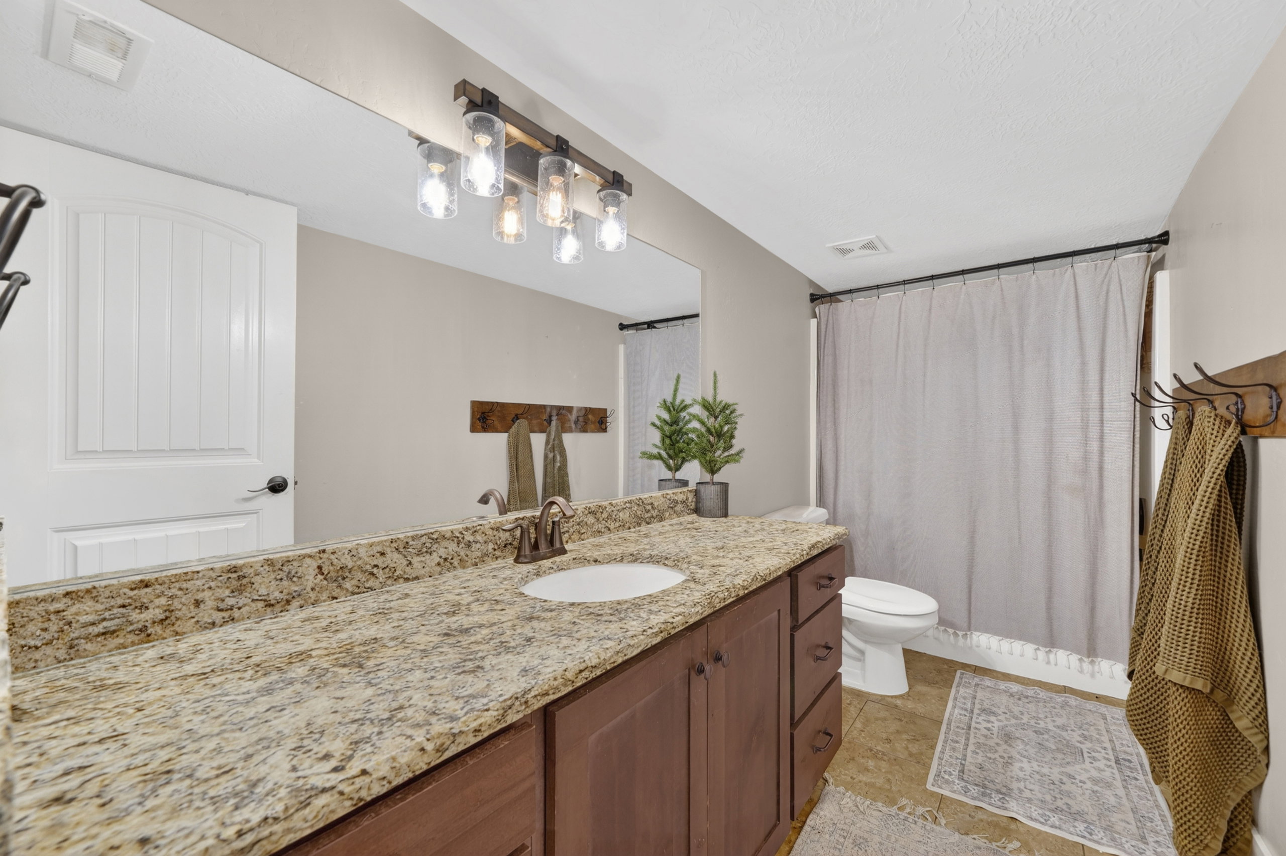 Bathroom featuring an extended vanity with a light-colored speckled countertop, an undermount sink, and a bronze-finish faucet