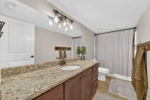 Bathroom featuring an extended vanity with a light-colored speckled countertop, an undermount sink, and a bronze-finish faucet