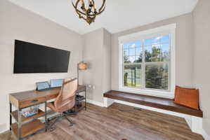 Room featuring a built-in window seat, large picture window, shiplap accent wall, and wood-finish flooring