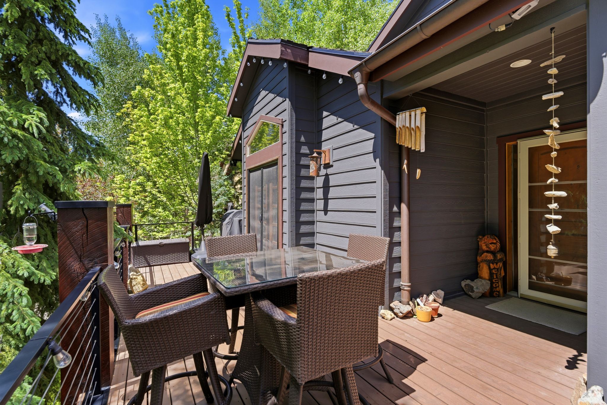 Spacious outdoor deck featuring wood-finish flooring, dark-toned siding, and a cable railing system