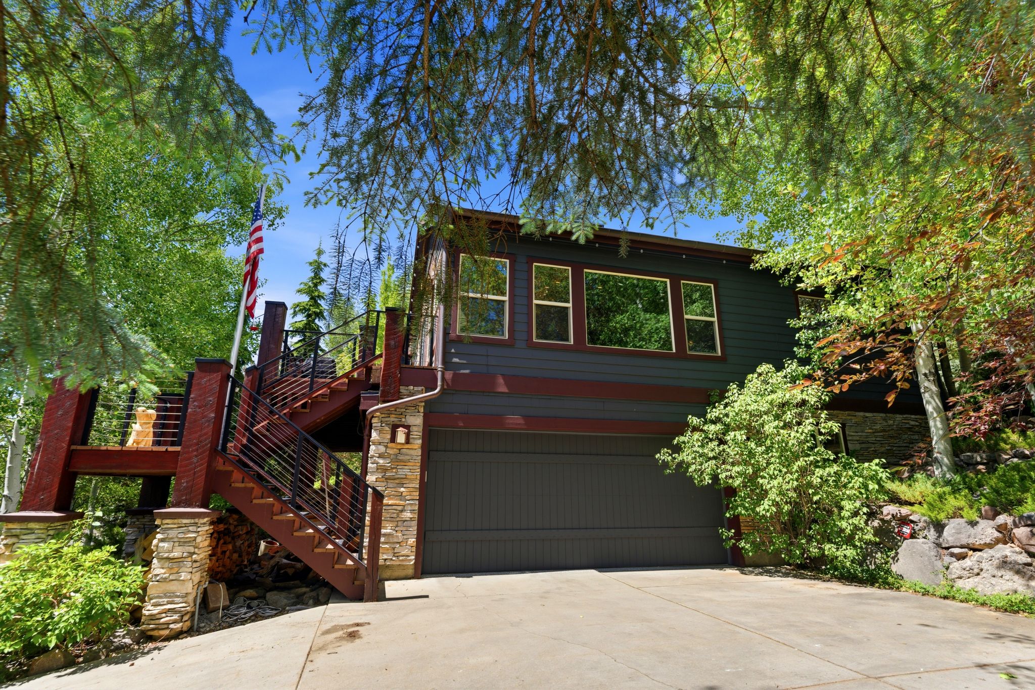 Multi-level residence featuring dark siding with contrasting trim, a two-car garage, and a concrete driveway