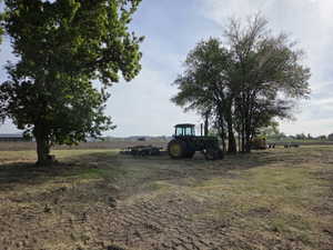Expansive open field with scattered mature trees and visible agricultural equipment