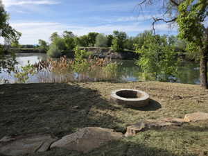 Waterside setting featuring a built-in stone fire pit, natural rock landscaping, and mature trees