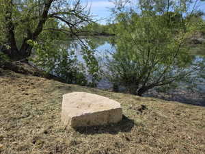 Waterfront property featuring mature trees and a substantial natural stone element