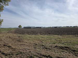 Expansive open field featuring dark, tilled soil and a partial fence line