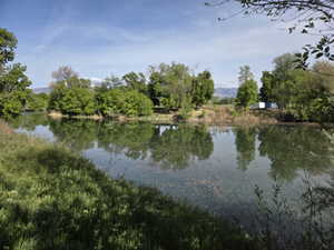 Expansive waterfront property featuring mature trees and a tranquil body of water reflecting the surrounding foliage
