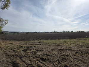 Expansive cleared land featuring cultivated soil and visible tire tracks