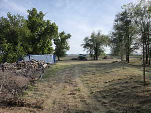 Expansive land parcel featuring mature trees, open areas, and two storage containers