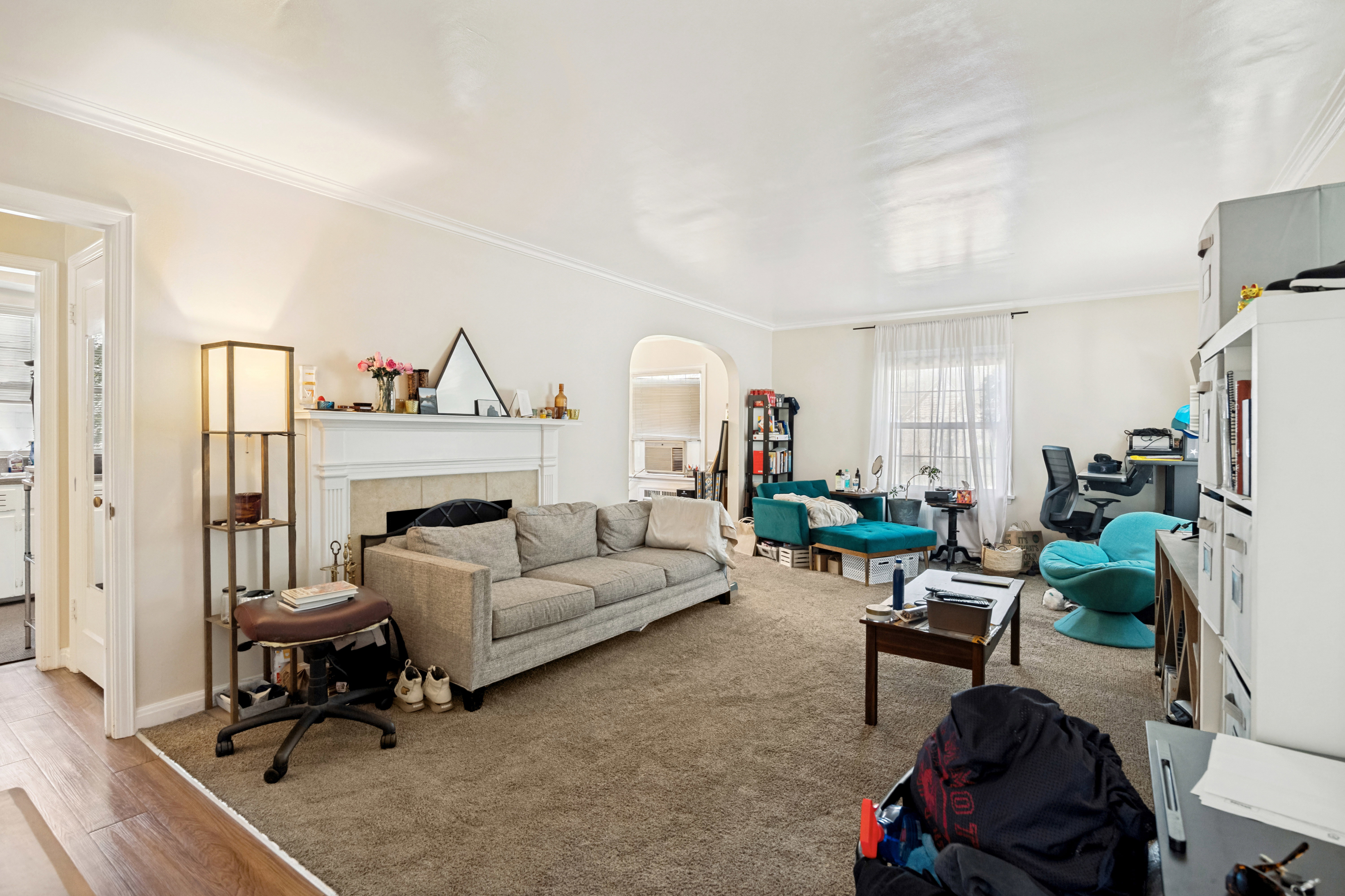Unit 1 Spacious living room featuring a traditional fireplace with a white mantel, archway detailing, and crown molding