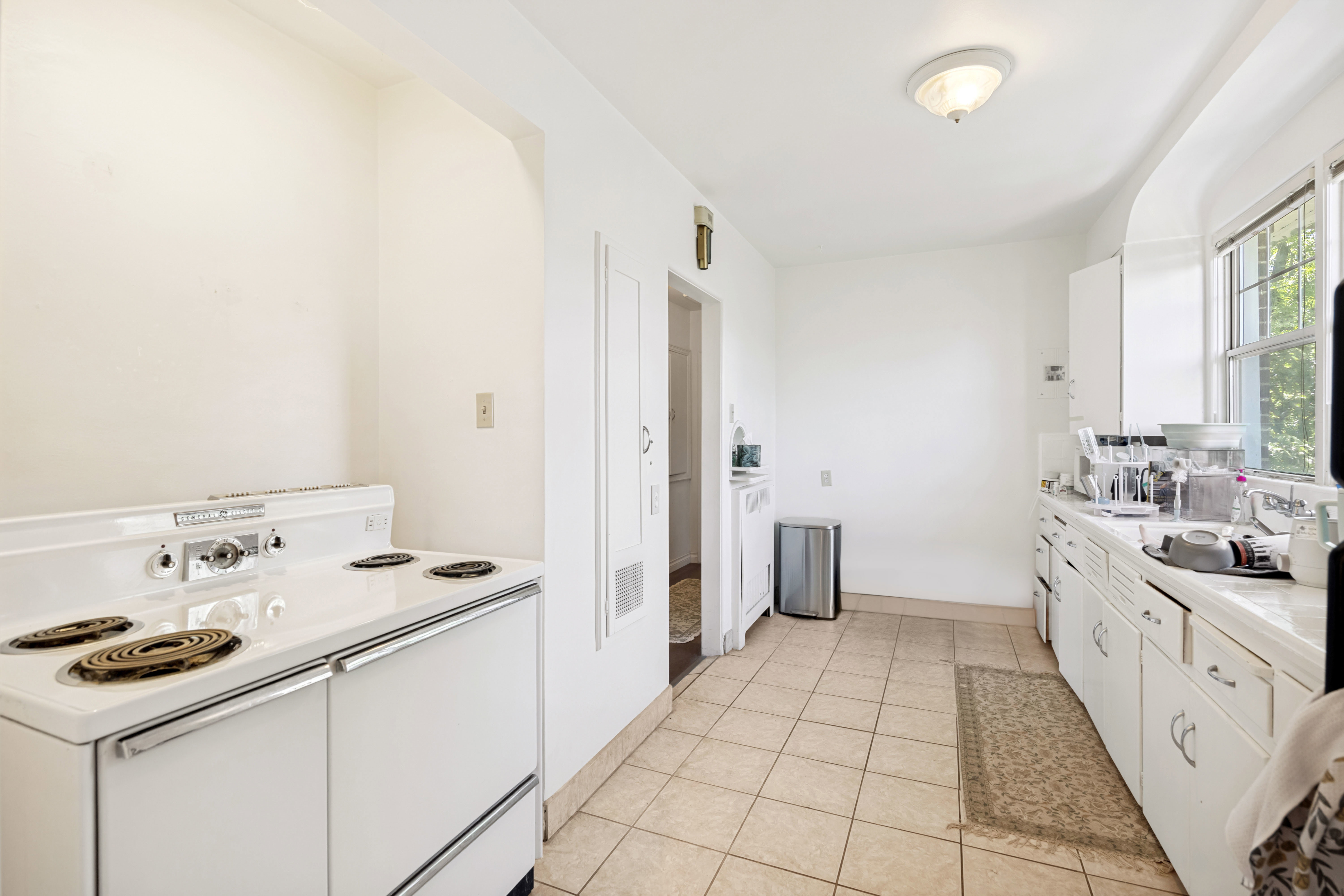 Unit 2  Kitchen with tile flooring, an electric range, built-in cabinetry, and a window