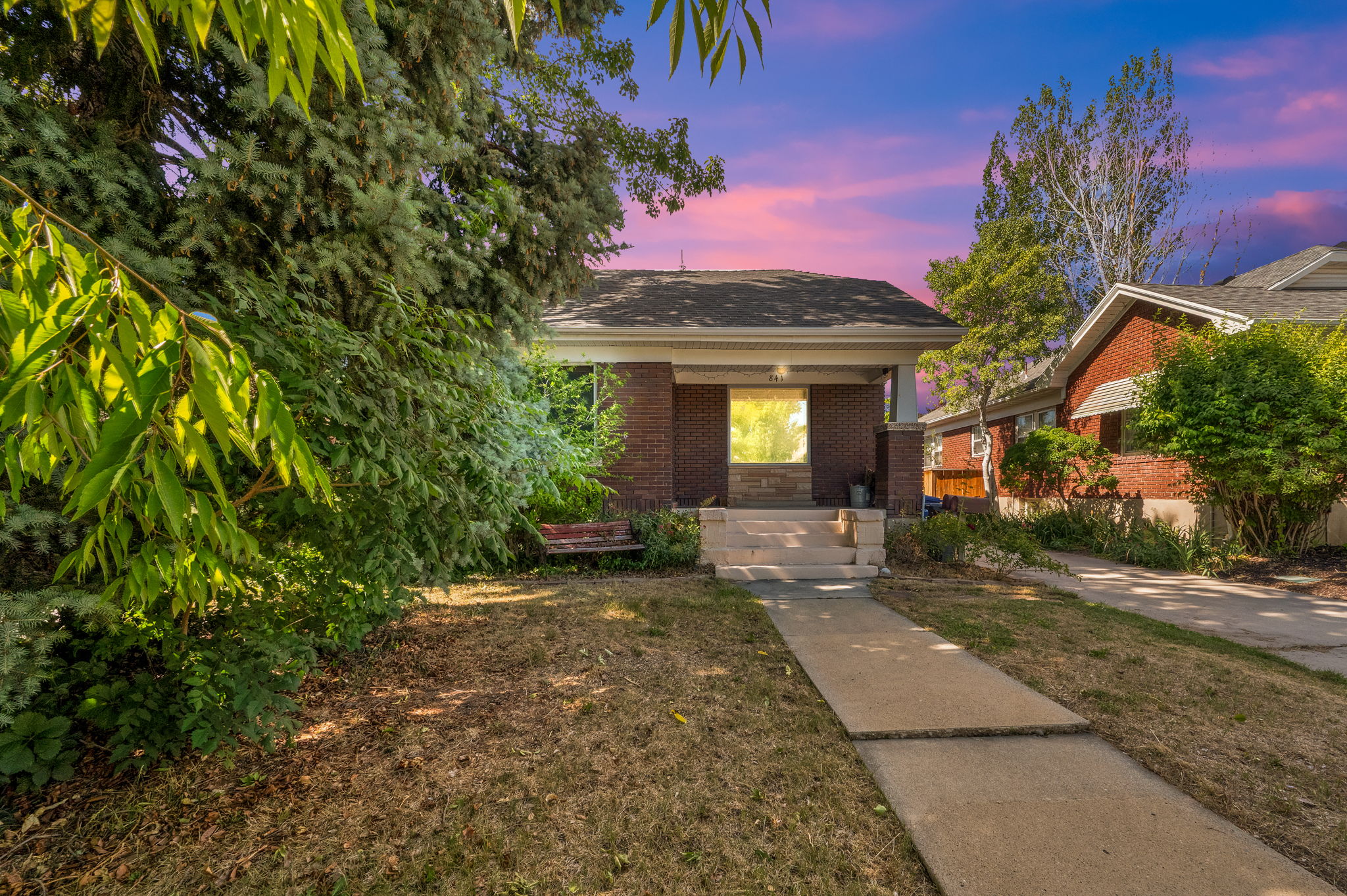 Brick-clad residence featuring a covered front porch with substantial columns