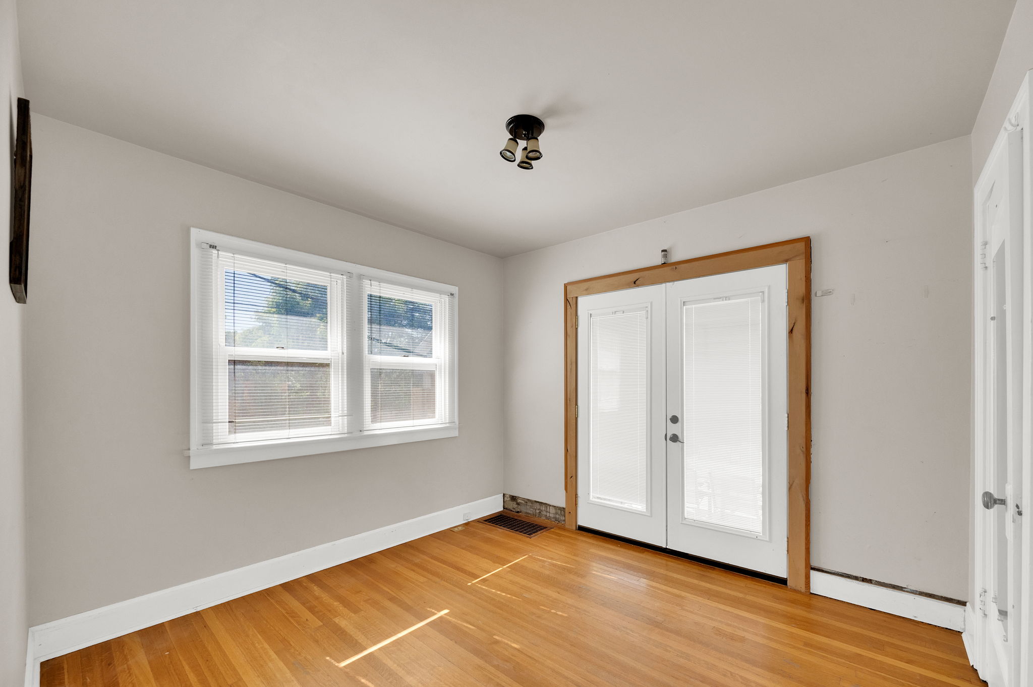 Hardwood flooring highlights this room featuring light gray walls, white trim, and a white ceiling