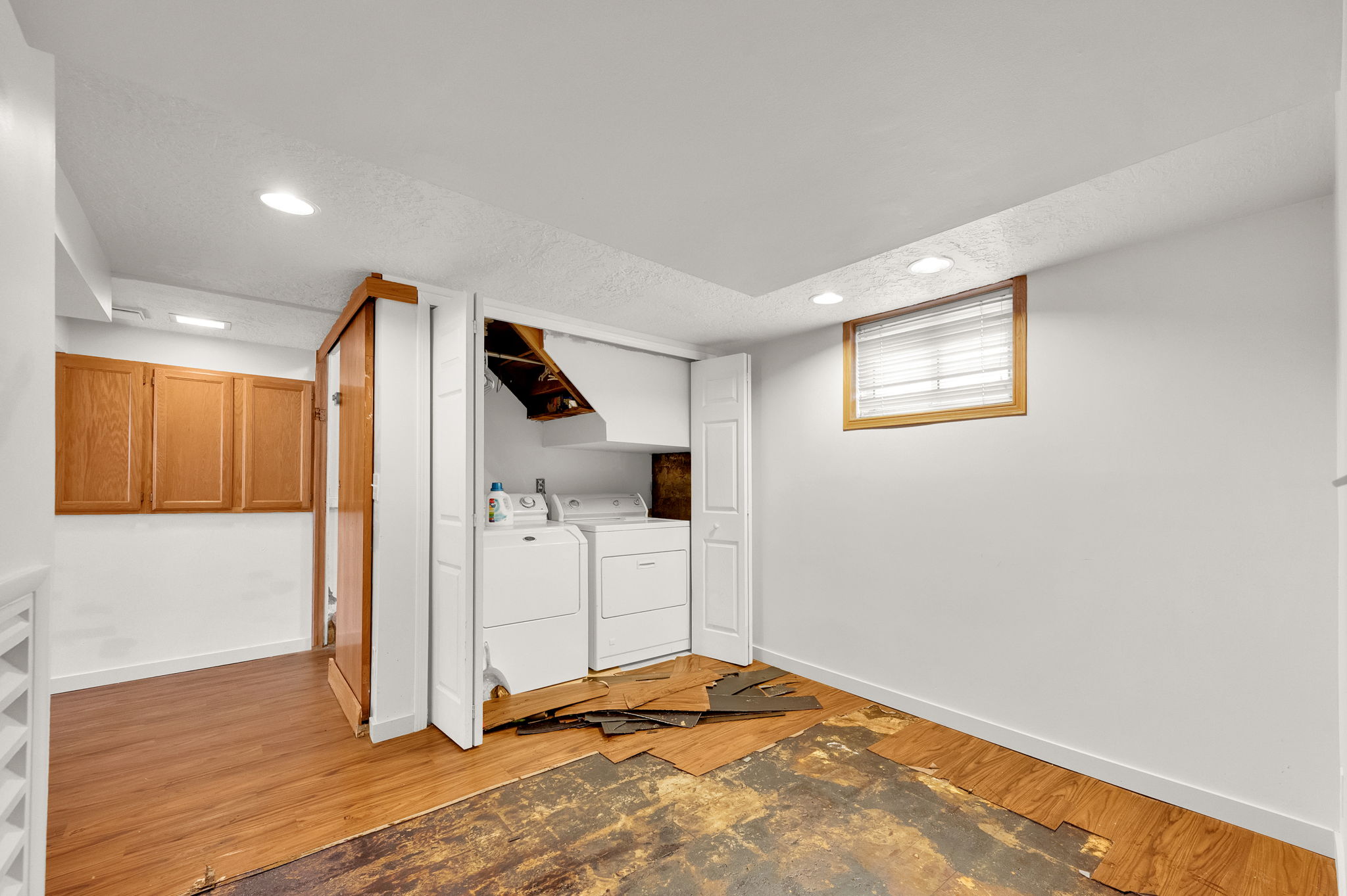 Laundry area with a window, recessed lighting, and wood-finish flooring