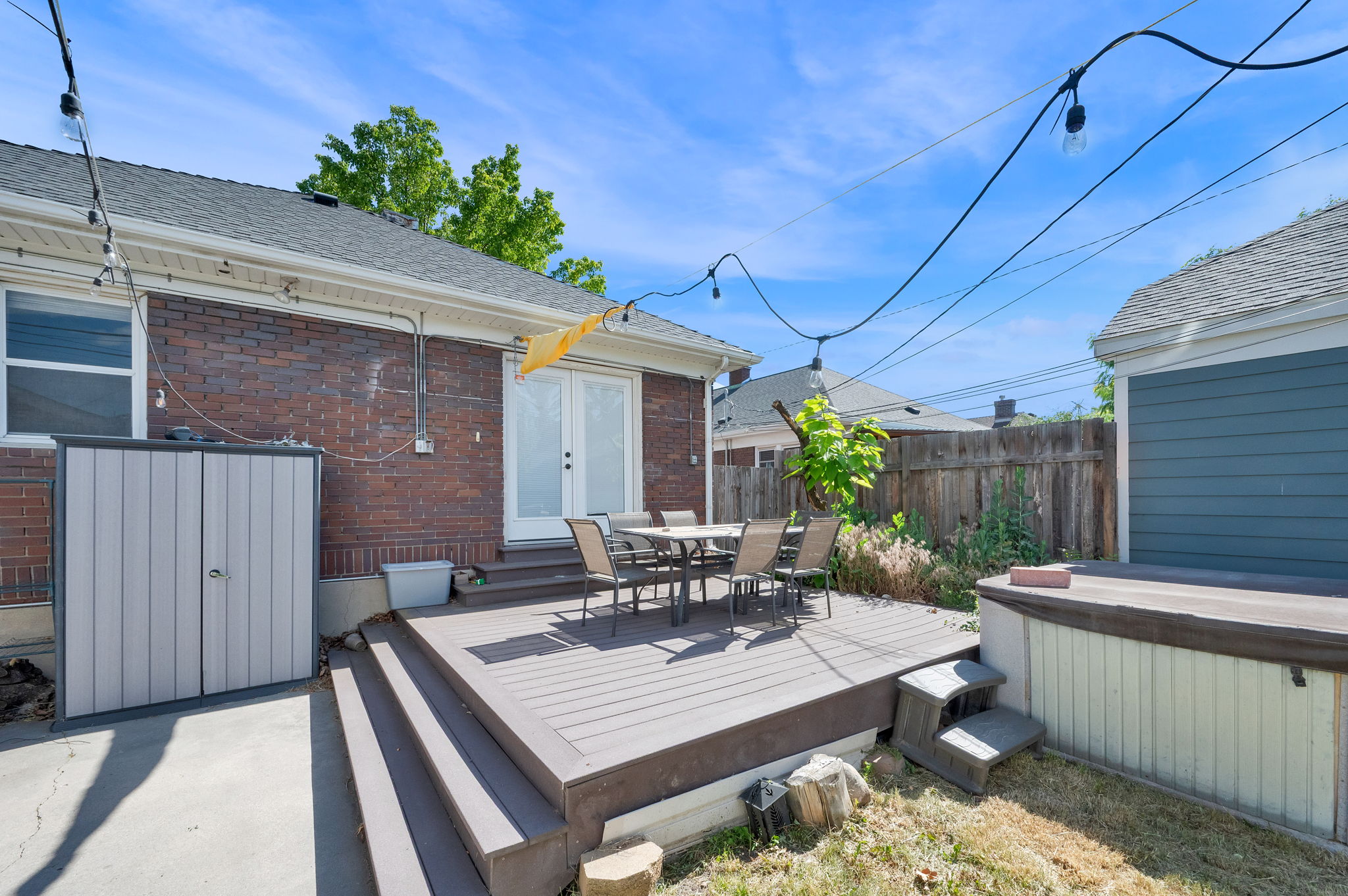 Rear exterior featuring a multi-level composite deck, brick siding, and double glass panel doors