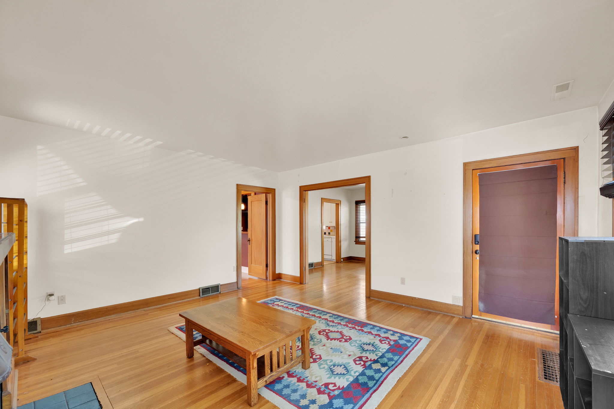 Spacious interior with wood-finish flooring, white walls, and warm wood trim