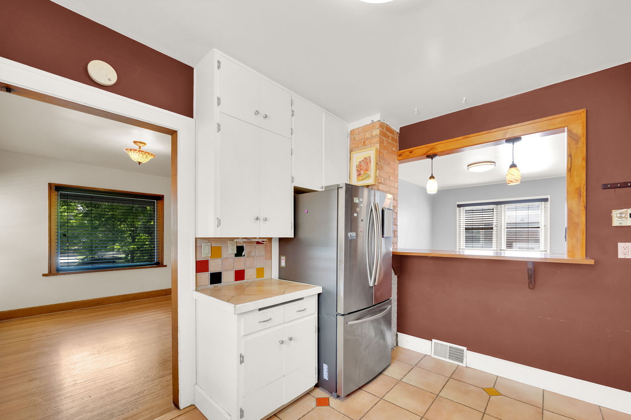 Kitchen featuring white cabinetry, tile flooring, and a pass-through window with a wood-finish frame