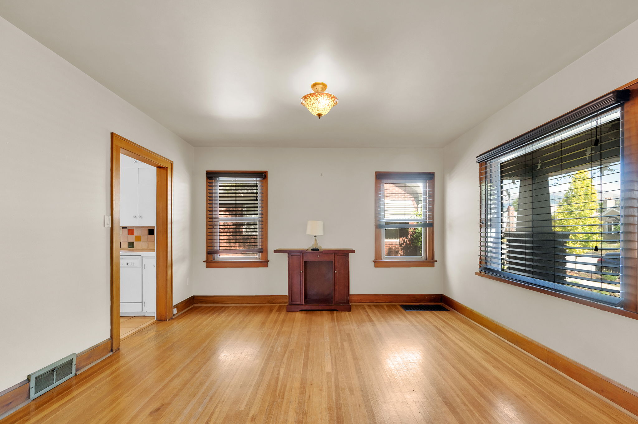 Spacious room featuring wood-finish flooring, white walls, and a decorative ceiling light fixture