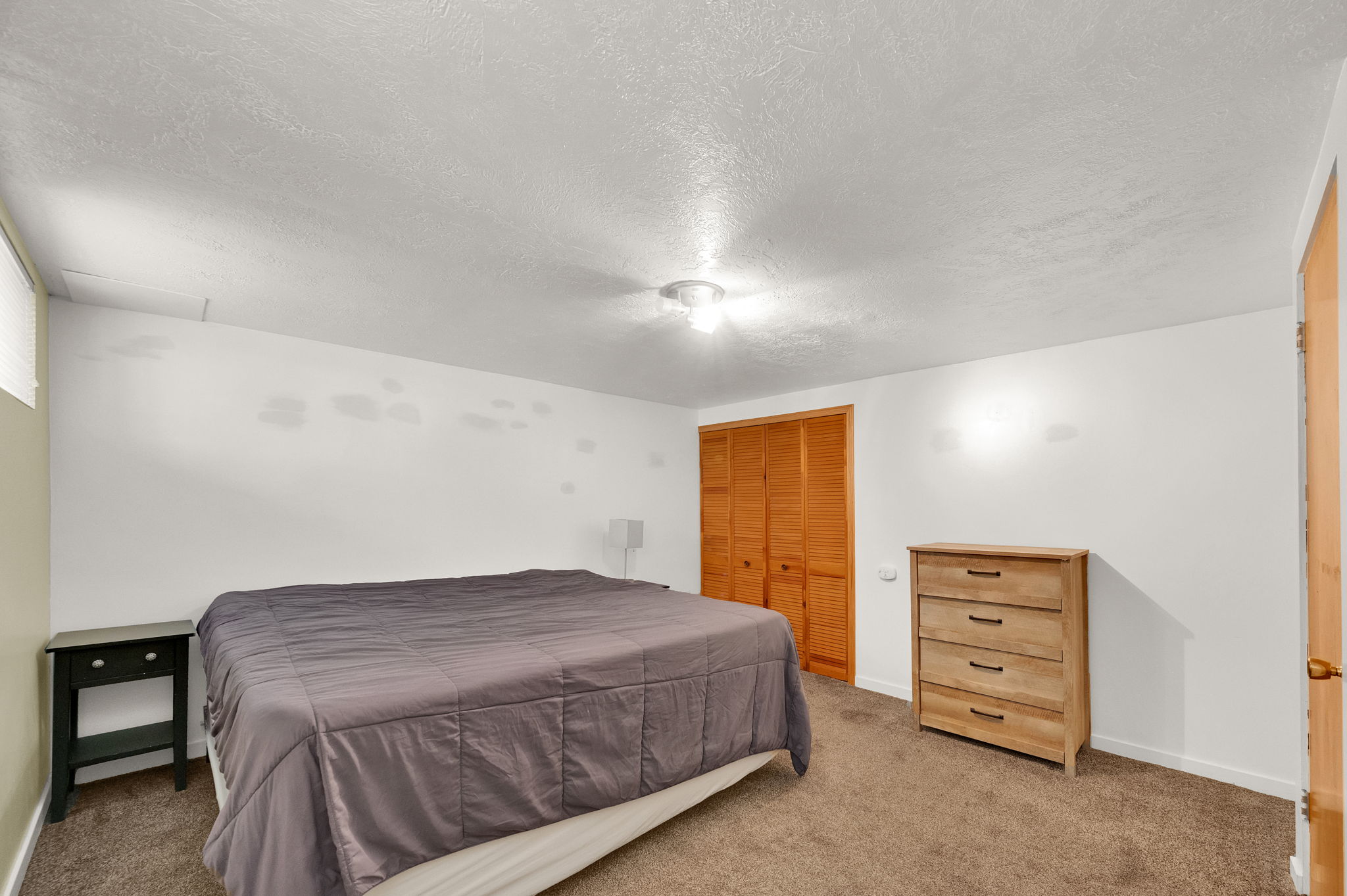 Interior space with a neutral color palette, featuring textured white walls and light brown carpeting