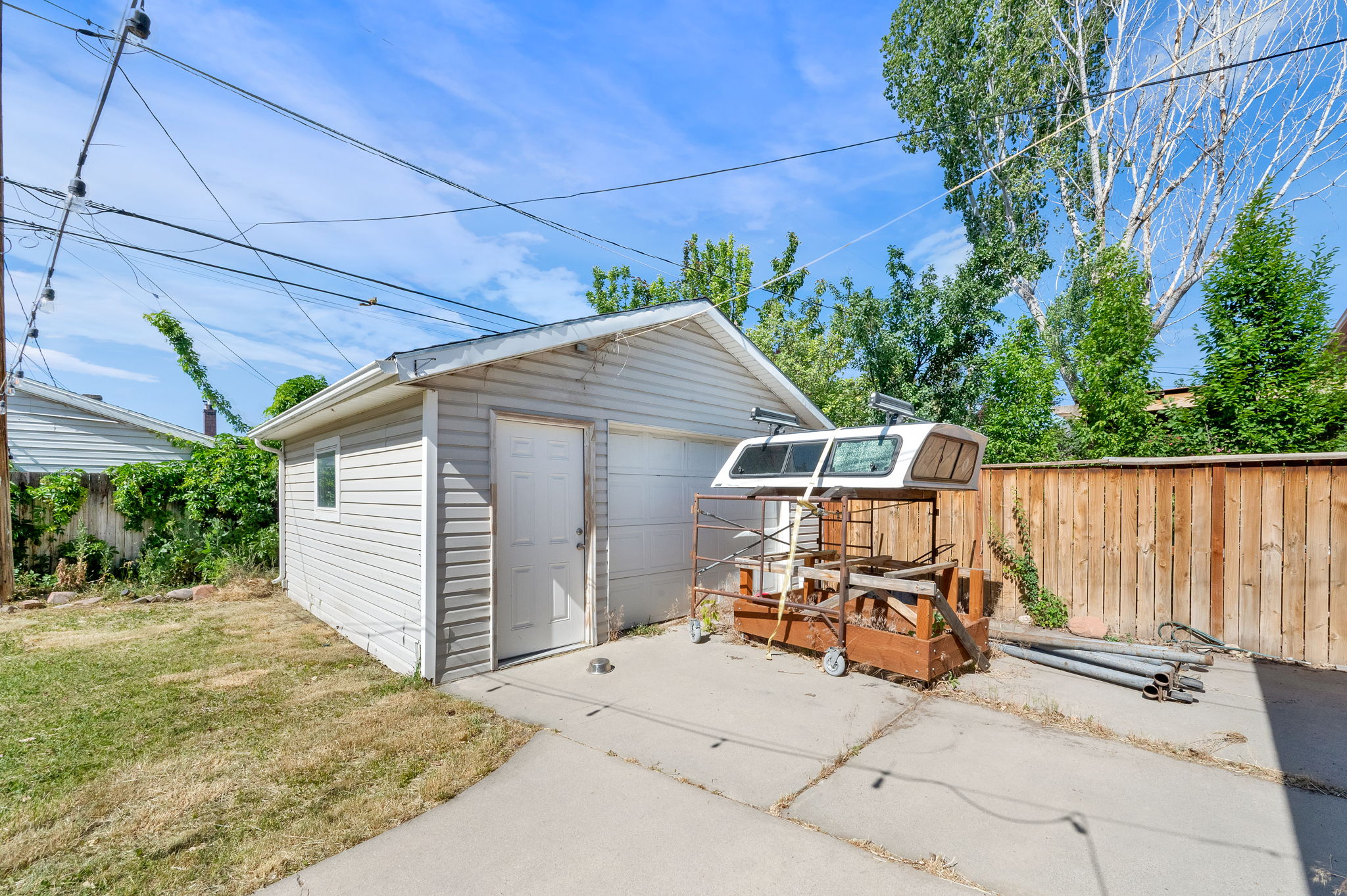 Detached garage featuring horizontal vinyl siding, an overhead garage door, a pedestrian access door, and a single window