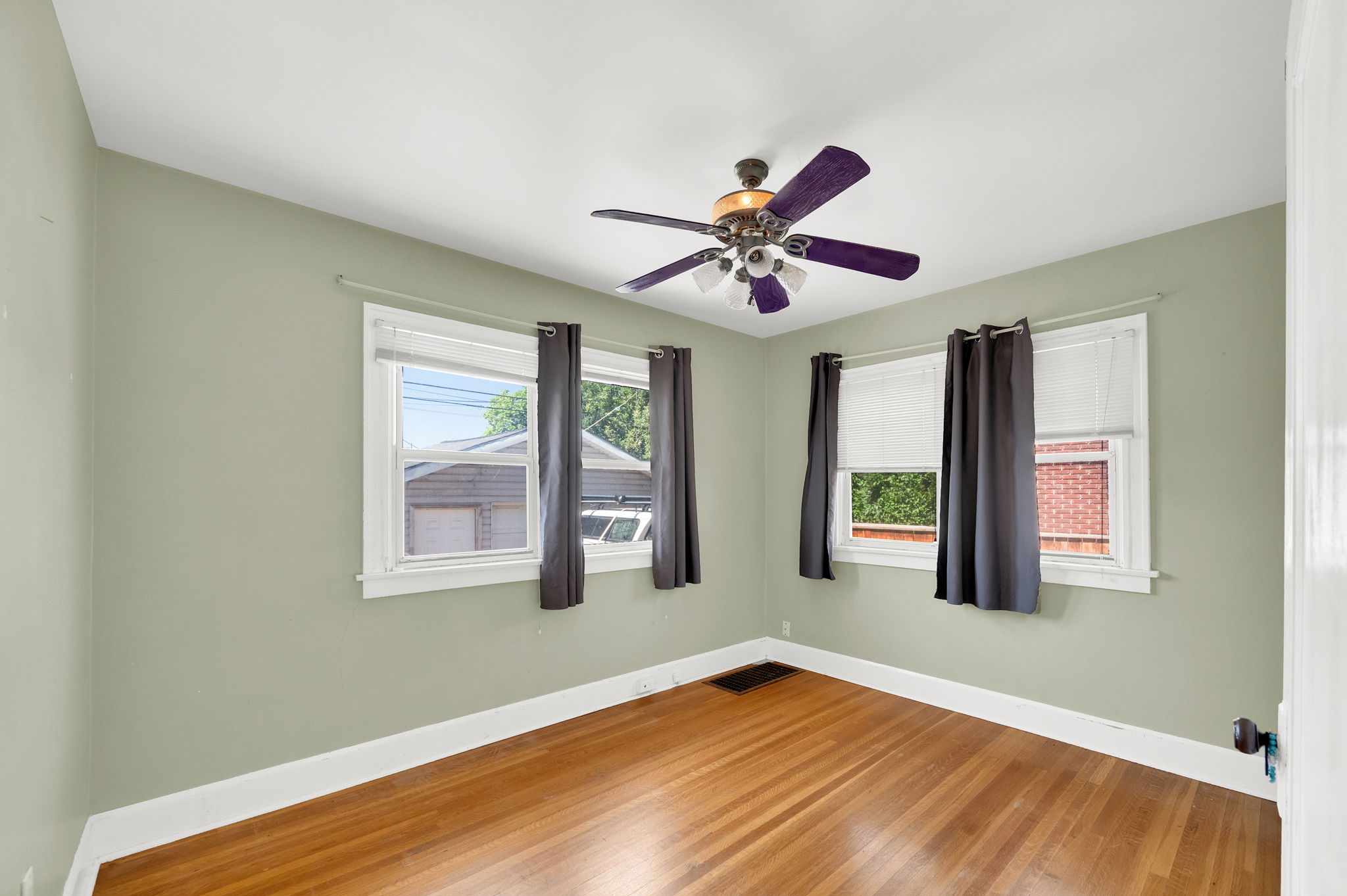 Room featuring wood-finish flooring, light green painted walls, white trim, and a ceiling fan with light fixture