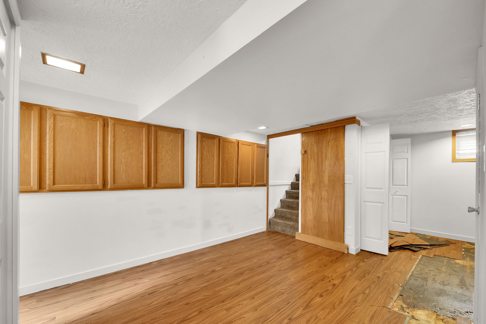 Room featuring wood-finish flooring, extensive upper cabinetry, and a carpeted staircase