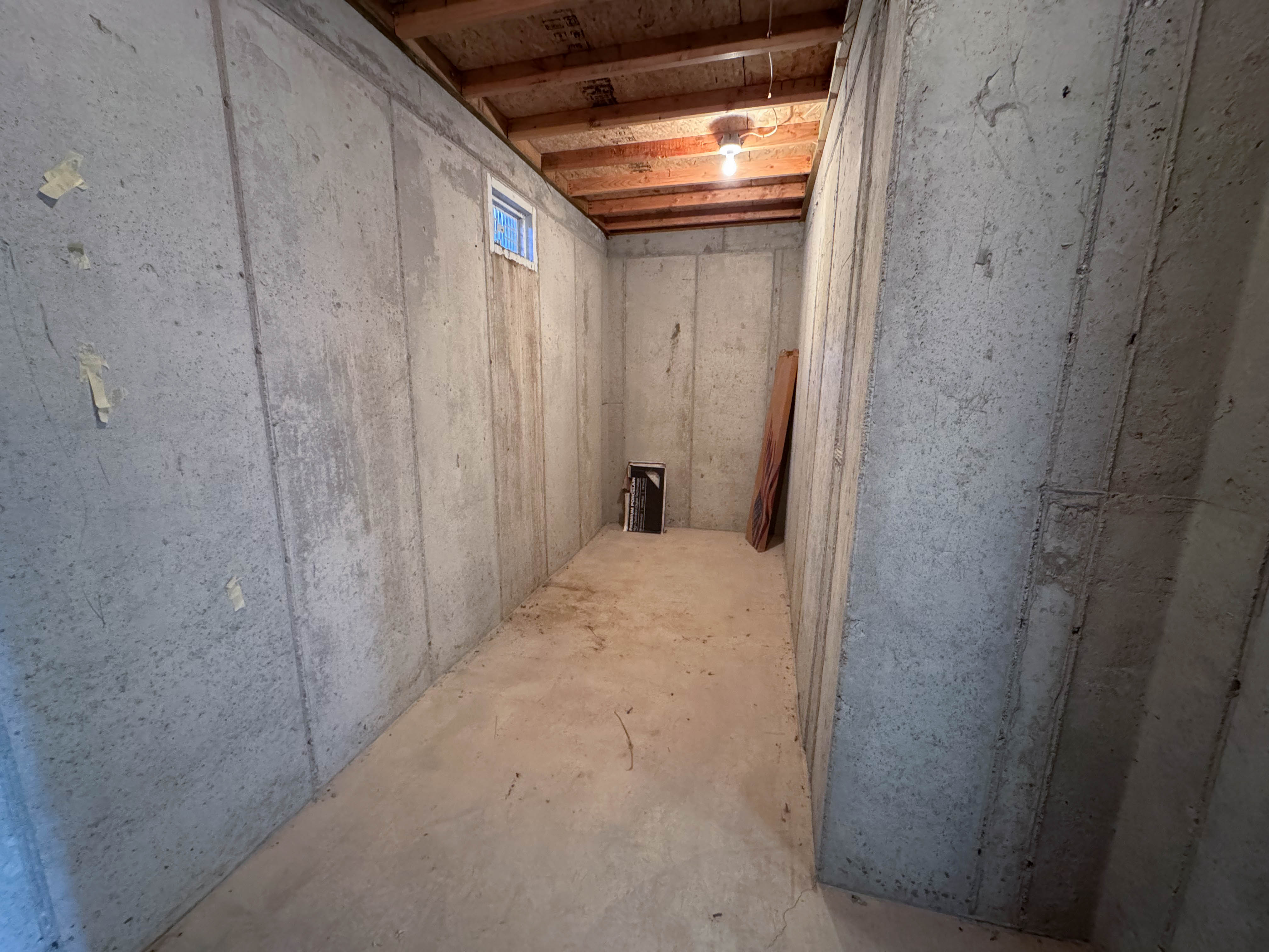 Unfinished basement room featuring poured concrete walls and concrete flooring