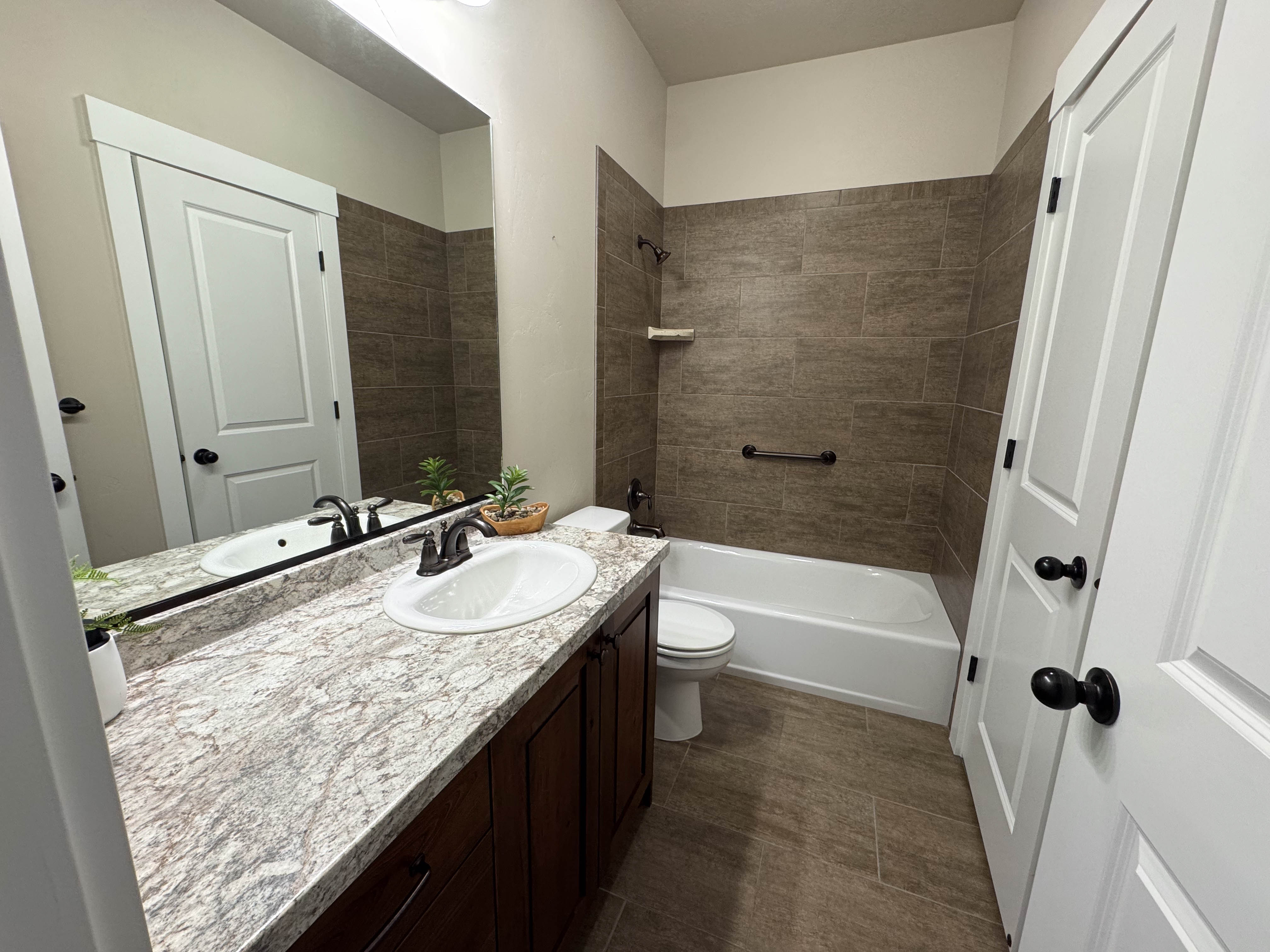 Bathroom featuring a single vanity with an undermount sink, a patterned countertop, and dark wood cabinetry