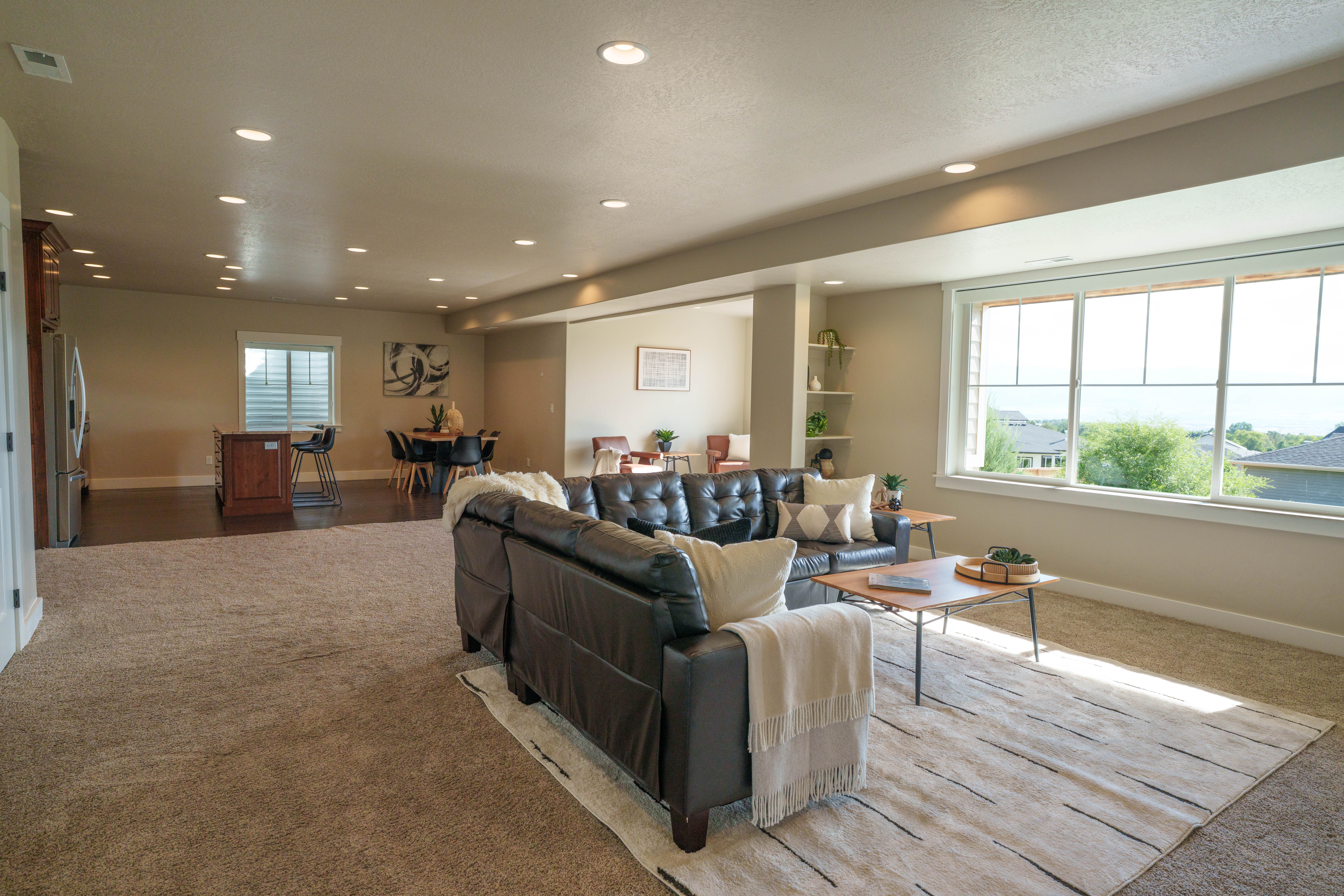 Open-concept living area with expansive windows, recessed lighting, carpet flooring, a dining area with wood-finish flooring, and built-in shelving