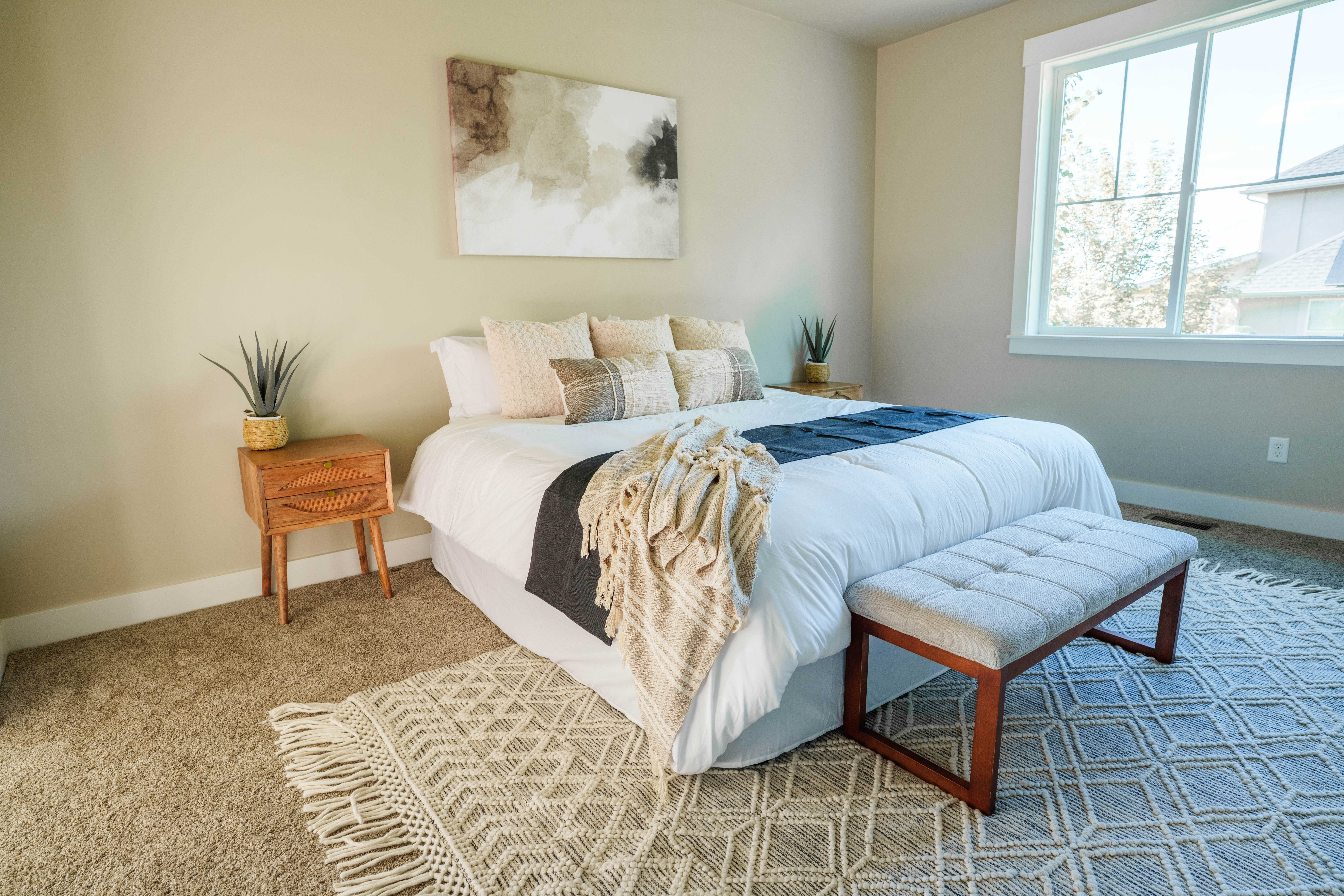 Warm neutral wall color, plush carpeting, and large windows with white trim