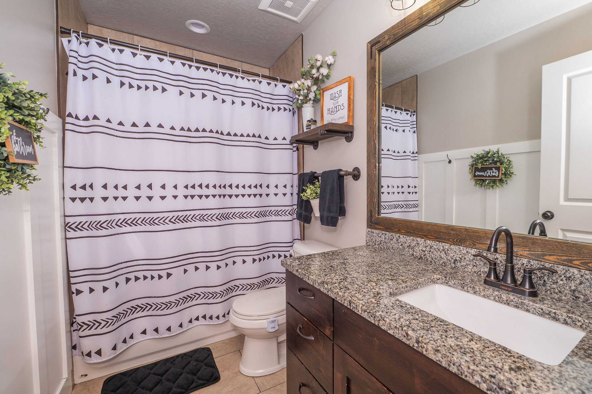 Bathroom featuring a bathtub with shower, a vanity with an integrated sink, a dark wood-finish cabinet, and a speckled countertop