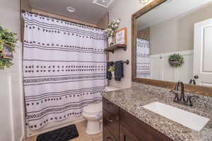 Bathroom featuring a bathtub with shower, a vanity with an integrated sink, a dark wood-finish cabinet, and a speckled countertop