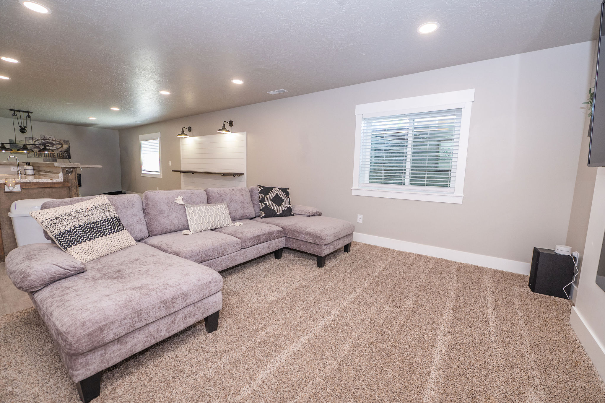 Carpeted living area featuring a window with blinds, recessed lighting, and white baseboards