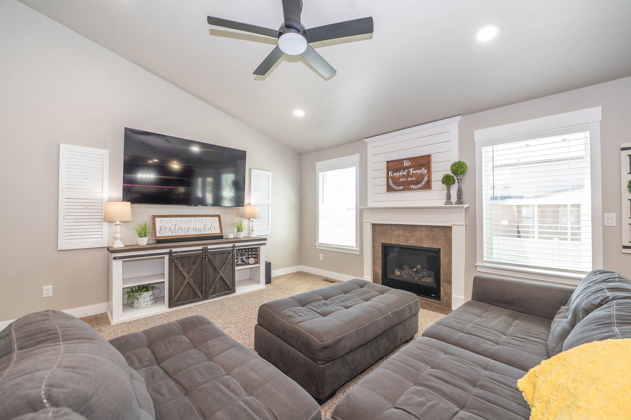 Spacious living area featuring a vaulted ceiling with a ceiling fan, recessed lighting, and carpet flooring