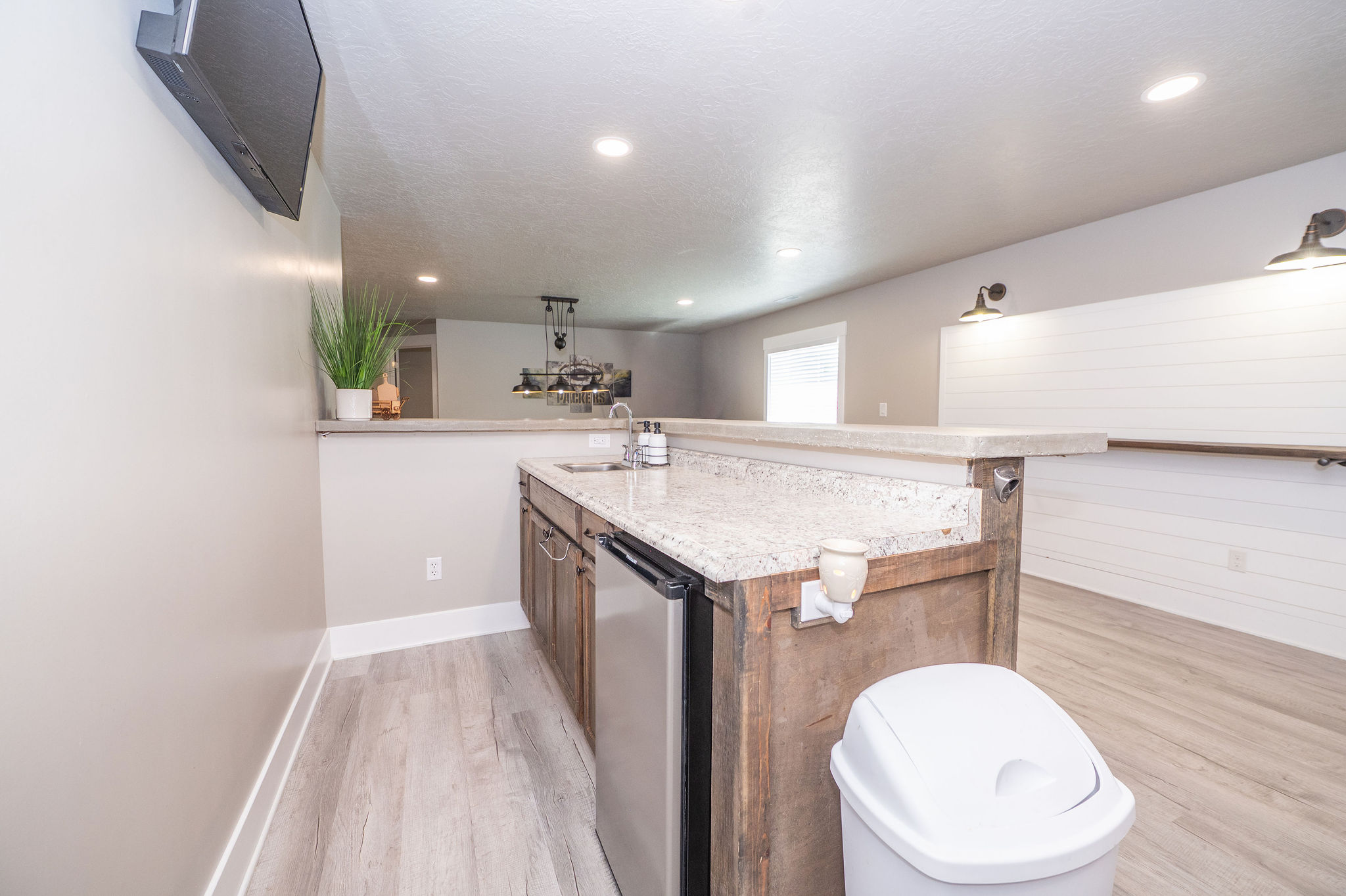 Wet bar featuring a granite-style countertop, undermount sink, built-in mini-refrigerator, and wood-finish cabinetry